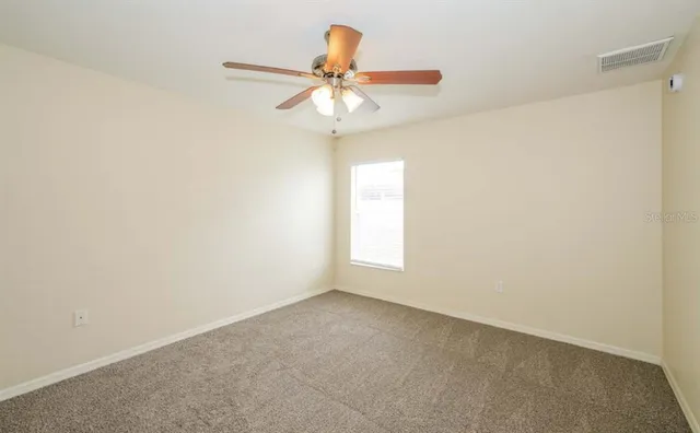 an empty room with a window and a chandelier fan