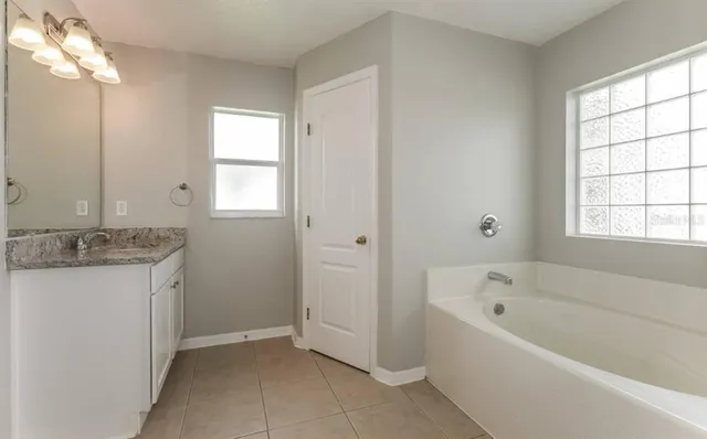 a bathroom with a granite countertop tub a sink and a window