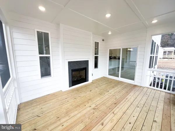 a view of an empty room with wooden floor and a fireplace