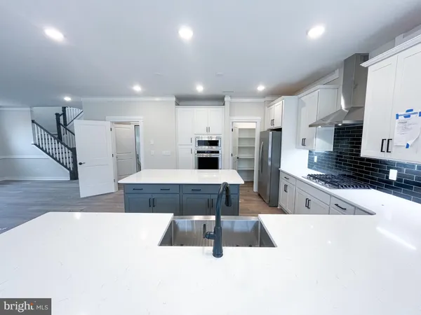 a large white kitchen with stainless steel appliances kitchen island a large counter top a stove and a sink