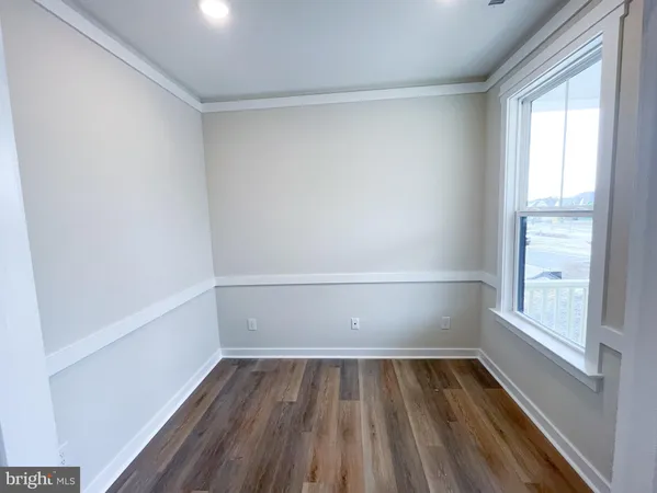 a view of an empty room with wooden floor and window