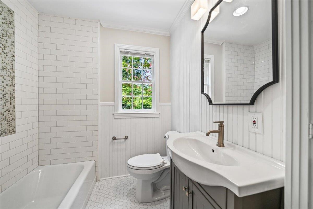 170 South Greer Street Memphis, TN 38111 - Photo 20 of 35 Bathroom featuring white subway tile surround, hexagonal floor tiling, a single vanity with an integrated sink, and an arched wall mirror