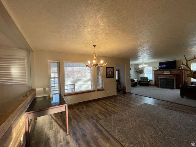 333 Lago Liberty Road Grace, ID 83241 - Photo 22 of 35 Unfurnished dining area with a chandelier, dark wood-type flooring, a fireplace, and a textured ceiling