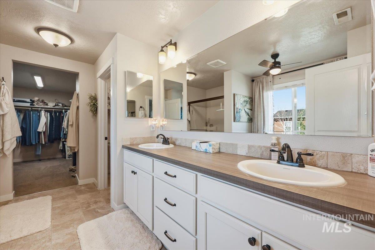 13314 Bloomfield Drive Caldwell, ID 83607 - Photo 10 of 32 Bathroom featuring double vanity, a spacious closet, a stall shower, ceiling fan, and a textured ceiling