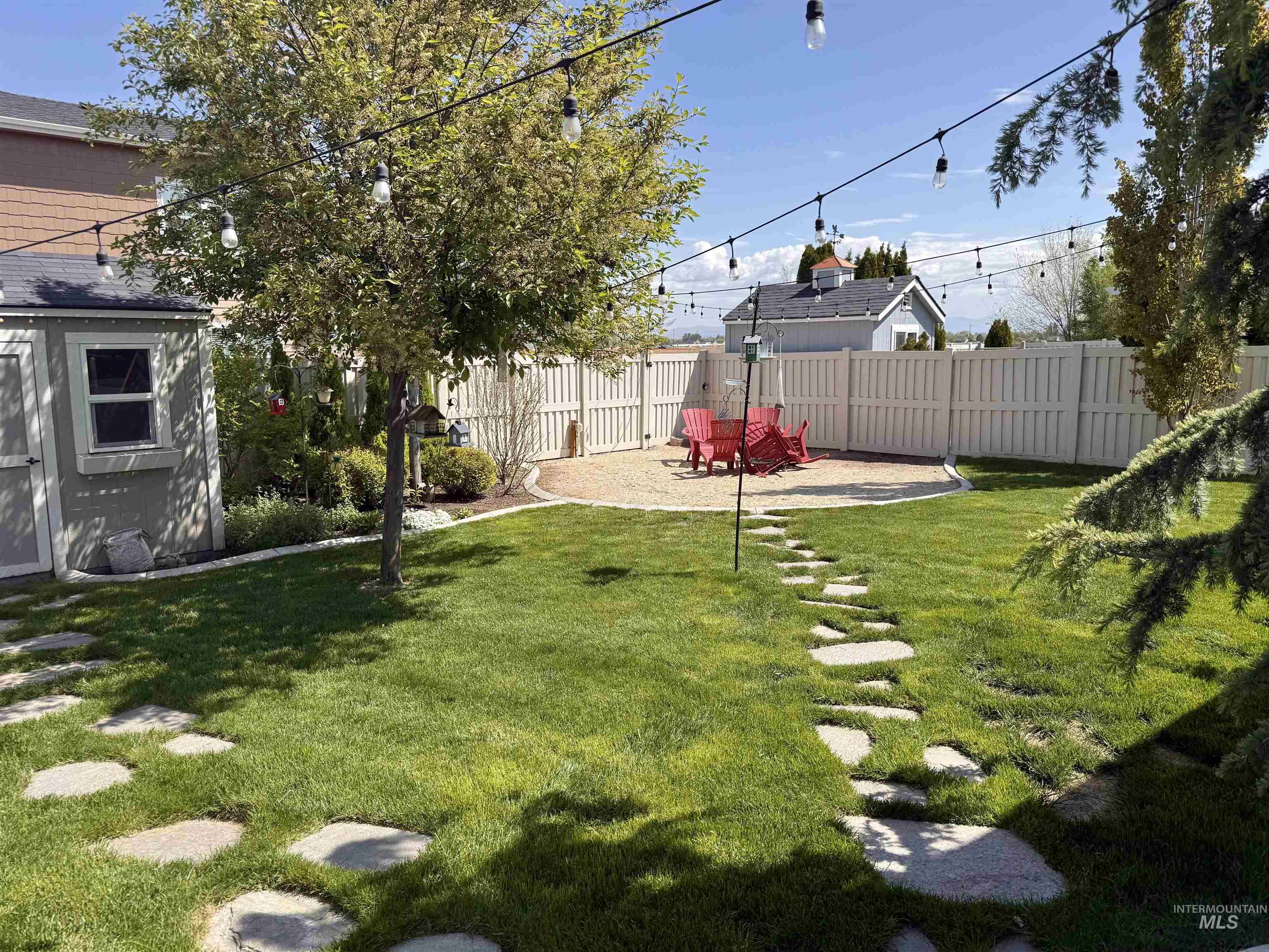 13314 Bloomfield Drive Caldwell, ID 83607 - Photo 23 of 32 Expansive backyard featuring a lush lawn, a stone paver pathway, string lighting, a gravel patio area, and a privacy fence
