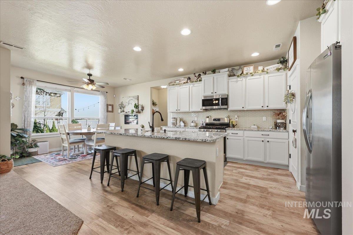13314 Bloomfield Drive Caldwell, ID 83607 - Photo 5 of 32 Kitchen with stainless steel appliances, a center island with sink, ceiling fan, white cabinetry, and a kitchen bar