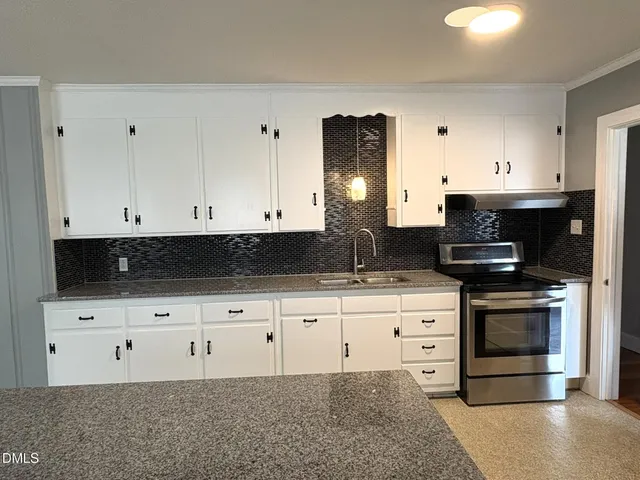 a kitchen with granite countertop white cabinets and stainless steel appliances