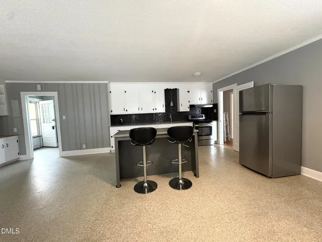 a kitchen with refrigerator and chairs