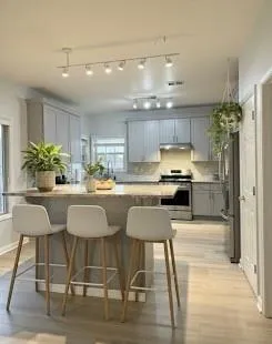 a kitchen with granite countertop a refrigerator and chairs