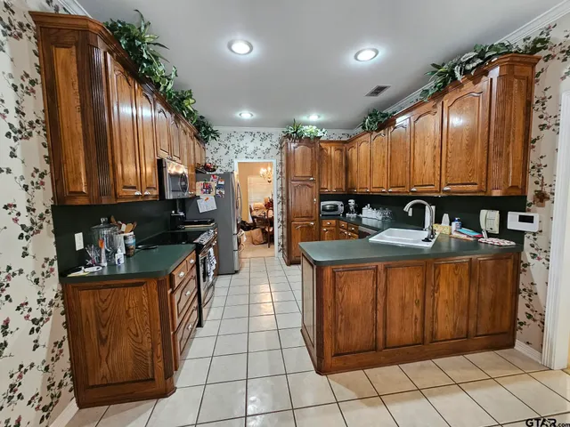 a kitchen with stainless steel appliances granite countertop a refrigerator a sink and wooden cabinets