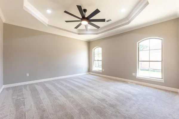 an empty room with windows and ceiling fan