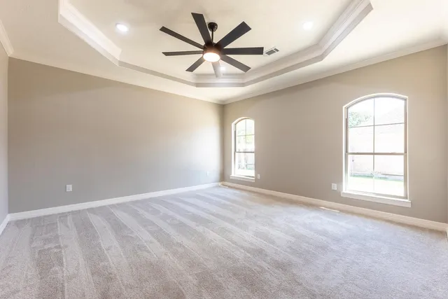 an empty room with windows and ceiling fan