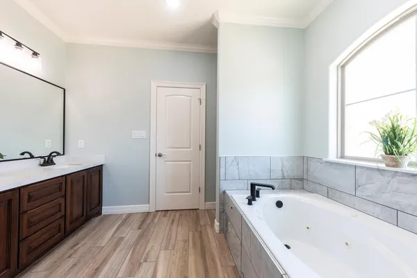 a bathroom with a tub a sink and mirror