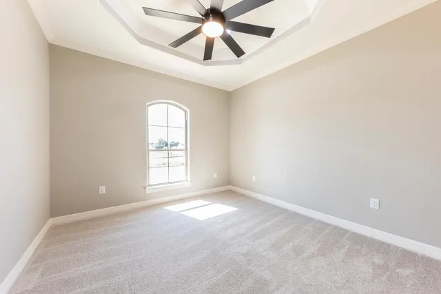 an empty room with chandelier fan and windows