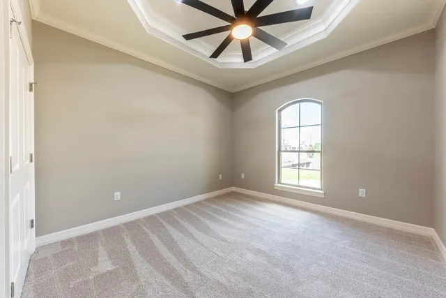 an empty room with chandelier fan and windows