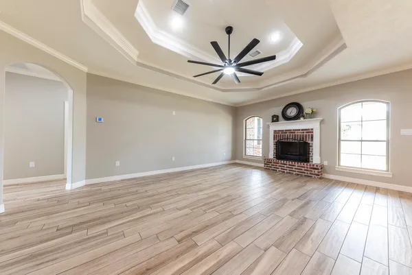 an empty room with wooden floor a fireplace and windows