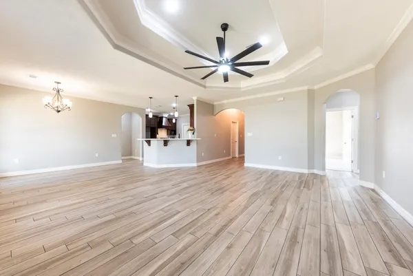 a view of a livingroom with a ceiling fan wooden floor and a ceiling fan