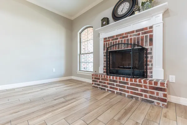 an empty room with wooden floor a fireplace and windows