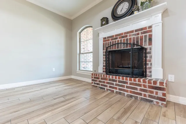 an empty room with wooden floor a fireplace and windows