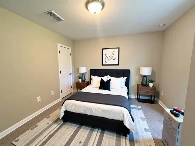 a bedroom with a bed and a lamp on the dresser