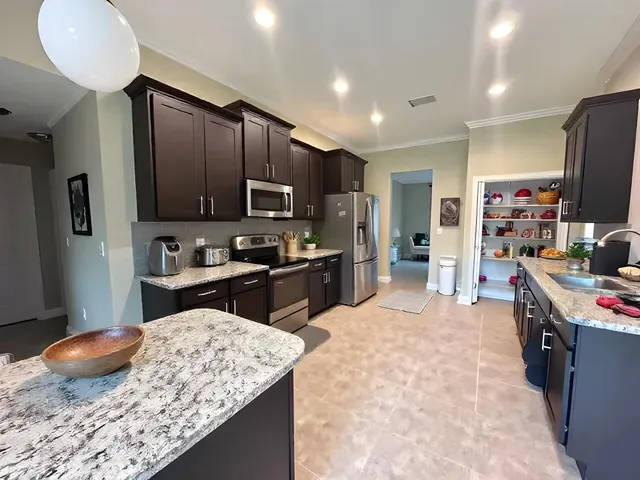 a kitchen with stainless steel appliances granite countertop a sink refrigerator stove and microwave