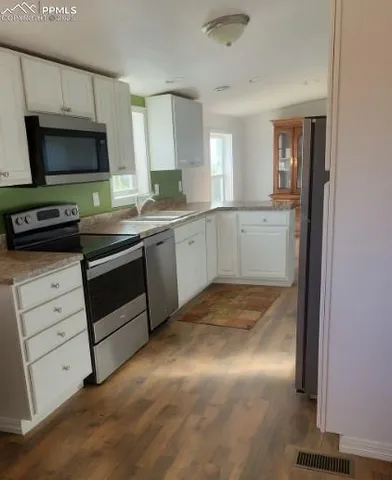 a kitchen with white cabinets and appliances