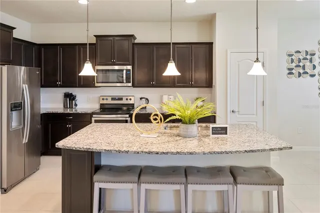 a kitchen with kitchen island granite countertop a sink a counter top space cabinets and stainless steel appliances
