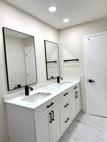 a bathroom with a granite countertop sink a mirror and shower