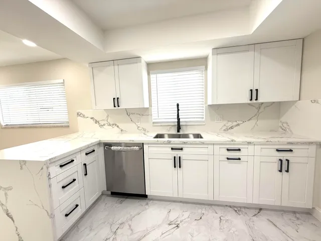 a kitchen with granite countertop white cabinets white appliances with a sink and dishwasher