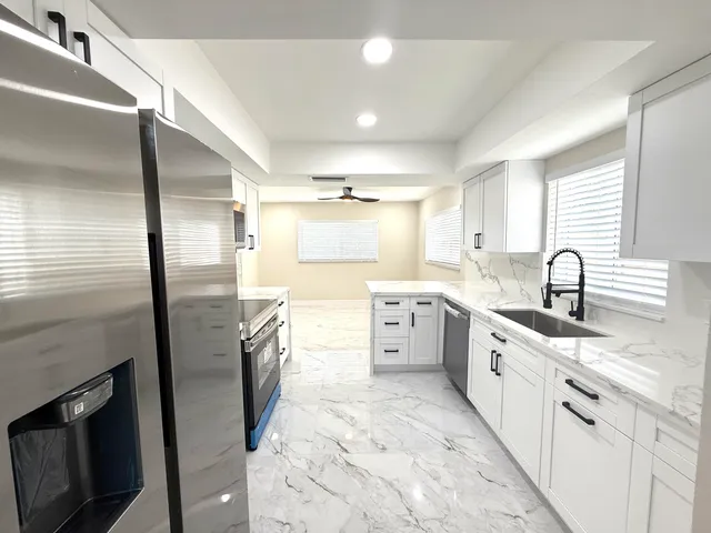 a large kitchen with stainless steel appliances granite countertop a sink stove and refrigerator