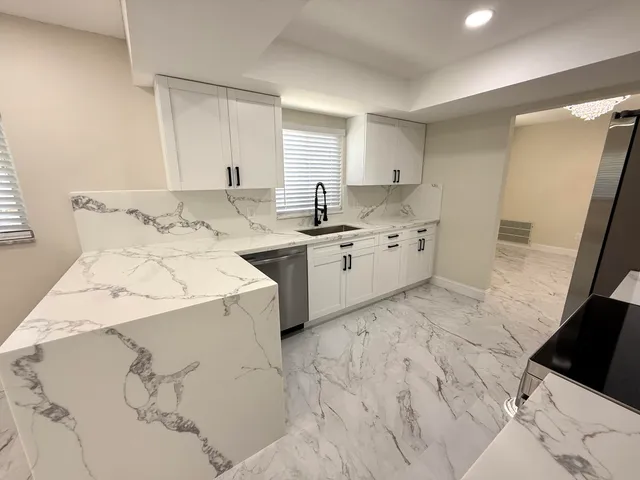 a large white kitchen with a sink and cabinets