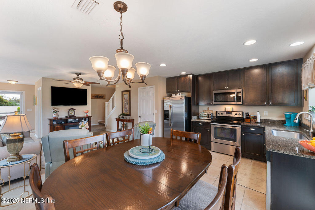 205 Islander Drive St. Augustine, FL 32080 - Photo 9 of 43 a kitchen with stainless steel appliances kitchen island granite countertop a sink a stove a dining table and chairs with wooden floor