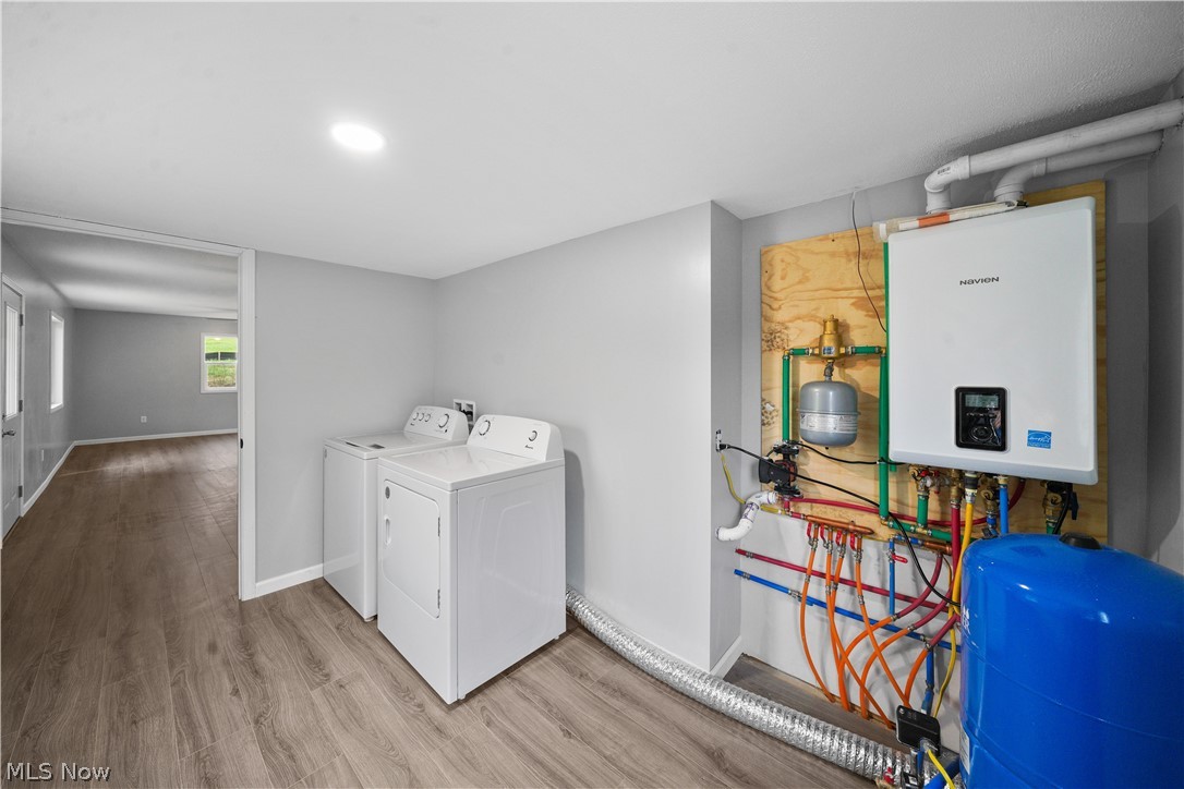 6180 Mackel Road Northeast Minerva, OH 44657 - Photo 5 of 8 Laundry room featuring washer and clothes dryer, tankless water heater, light wood-type flooring, and hookup for a washing machine
