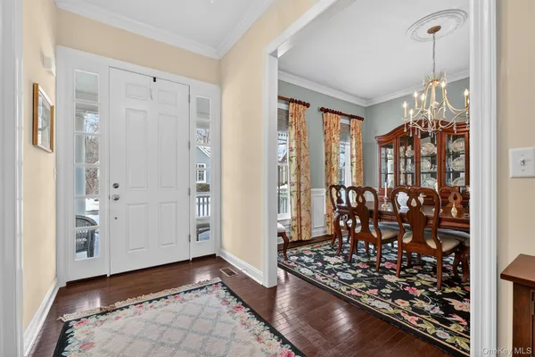 a view of a hallway with wooden floor and a livingroom with furniture