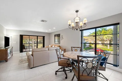 a view of a dining room with furniture a chandelier and large windows