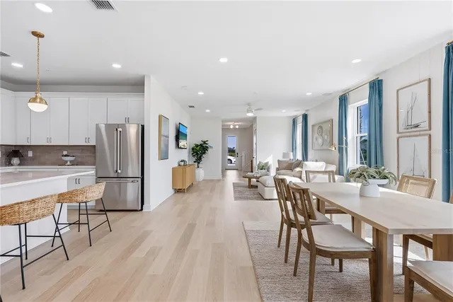 a kitchen with stainless steel appliances granite countertop a stove top oven a refrigerator a sink and white cabinets with wooden floor