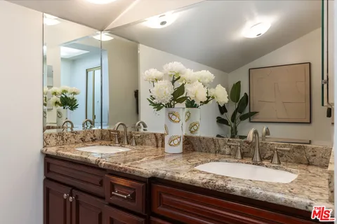 a bathroom with a granite countertop double vanity and a mirror