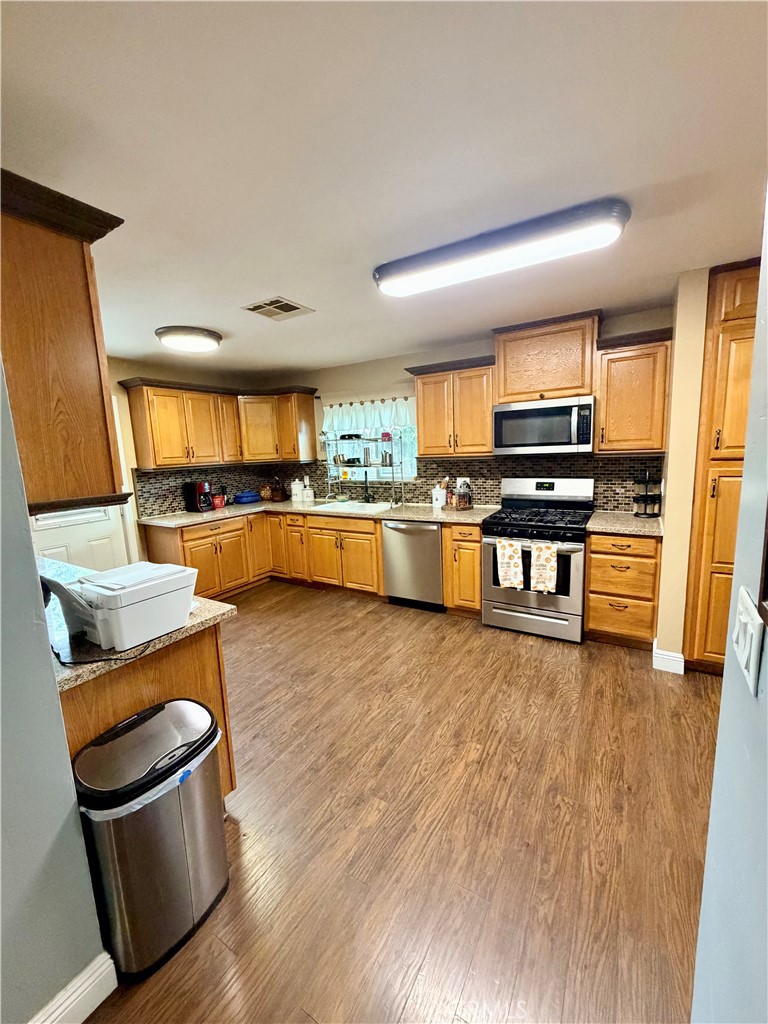 1896 Maryvale Lane Hemet, CA 92544 - Photo 9 of 33 a kitchen with stainless steel appliances wooden floors and wooden cabinets