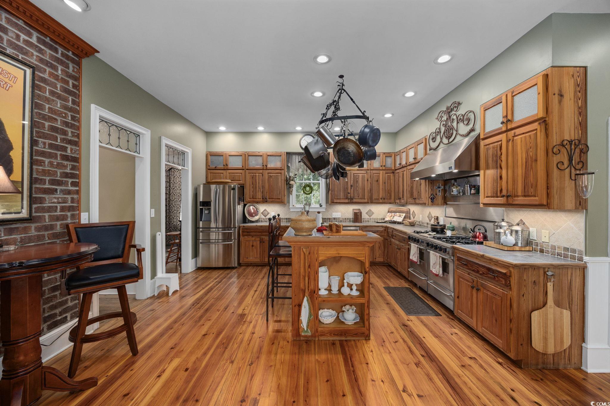 3750 Highway 813 Conway Sc 29526 Conway, SC 29526 - Photo 12 of 40 Kitchen with brown cabinets, a breakfast bar area, appliances with stainless steel finishes, under cabinet range hood, and light wood finished floors