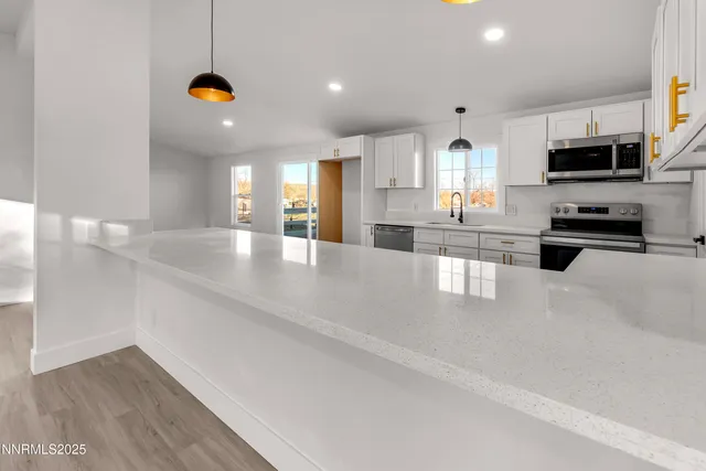 a large white kitchen with kitchen island a sink a stove and white cabinets