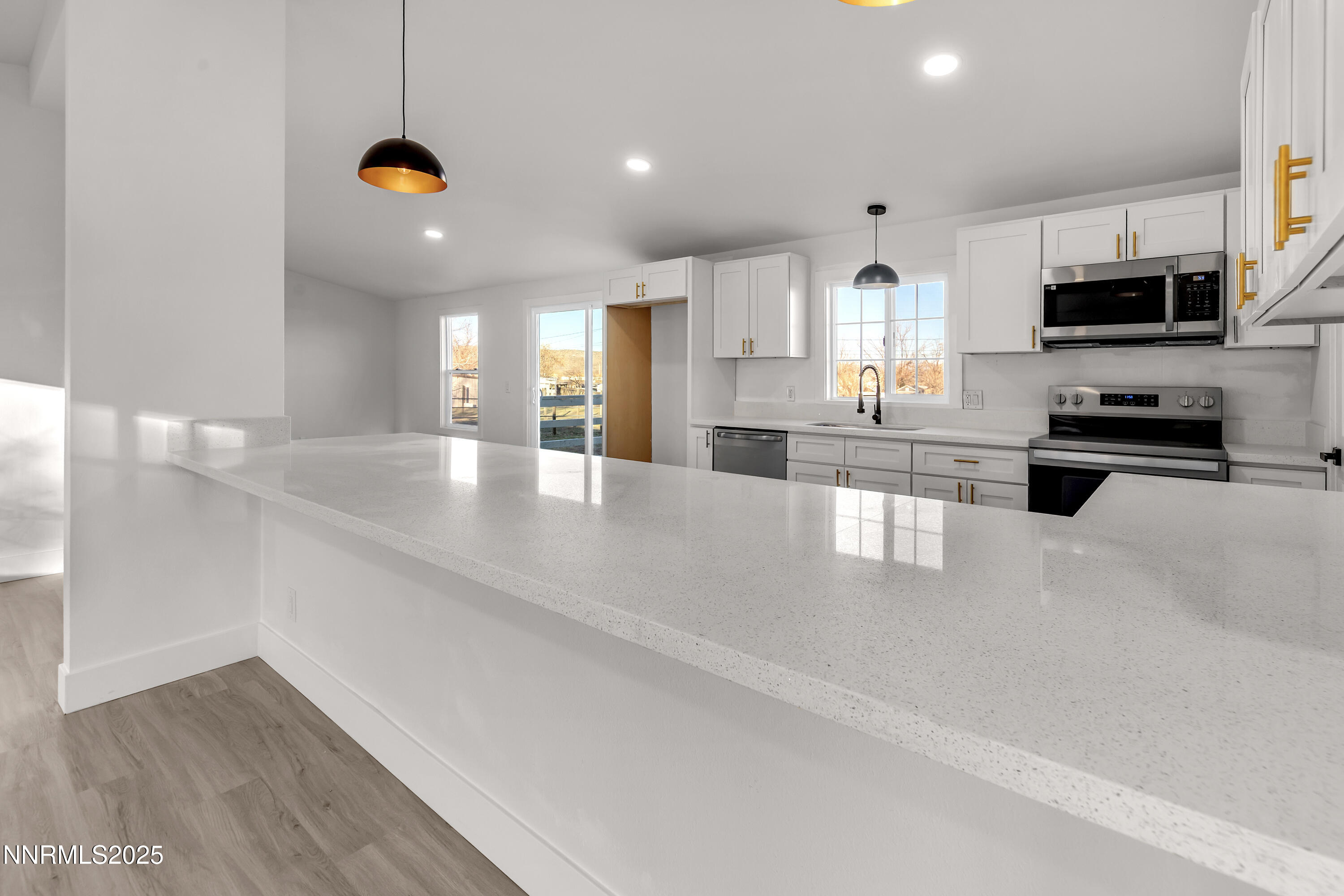a large white kitchen with kitchen island a sink a stove and white cabinets
