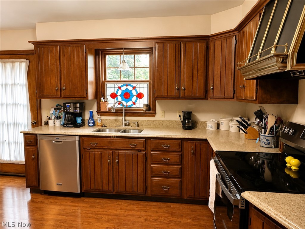 6155 Gibson Road Canfield, OH 44406 - Photo 19 of 43 Kitchen featuring wood-finish cabinetry, light-toned countertops, a stainless steel dishwasher, a stainless steel electric range, and wood-finish flooring