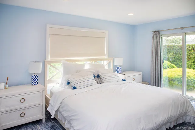 a large white bed sitting in a bedroom next to a window