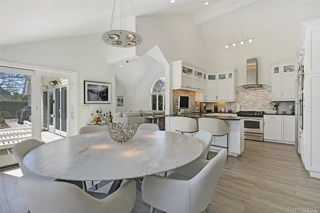 a dining room with kitchen island stainless steel appliances furniture large window and wooden floor