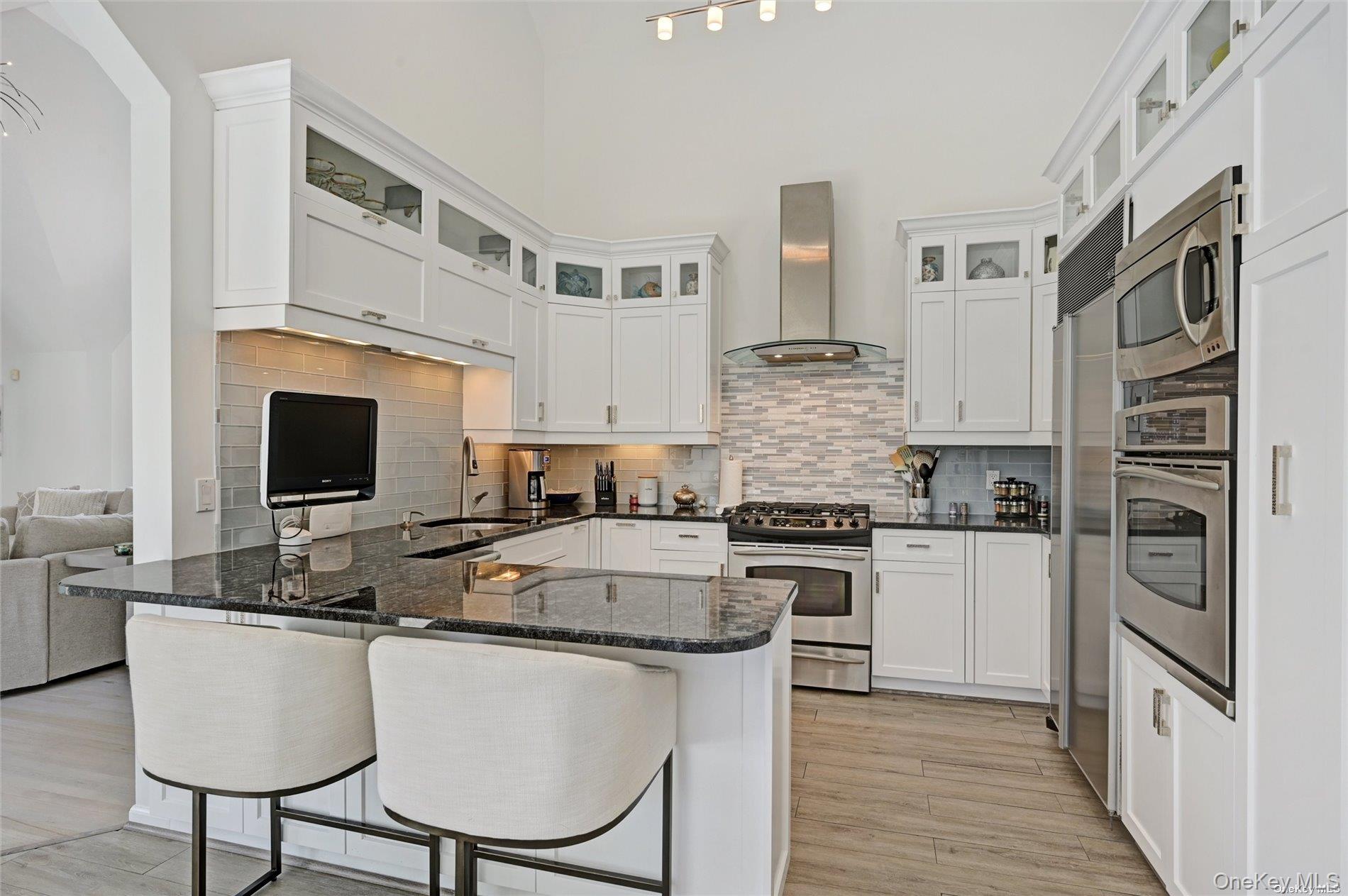 16 Laila Lane Remsenburg, NY 11960 - Photo 9 of 36 a kitchen with stainless steel appliances granite countertop a stove top oven a sink dishwasher and a refrigerator with wooden floor
