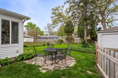 a view of a chair and table in backyard of the house