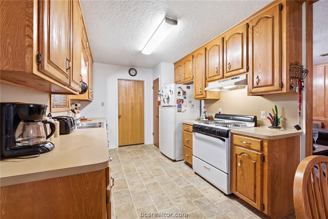706 Mesquite Street Calvert, TX 77837 - Photo 12 of 23 a kitchen with stainless steel appliances granite countertop a refrigerator a stove and a sink with cabinets
