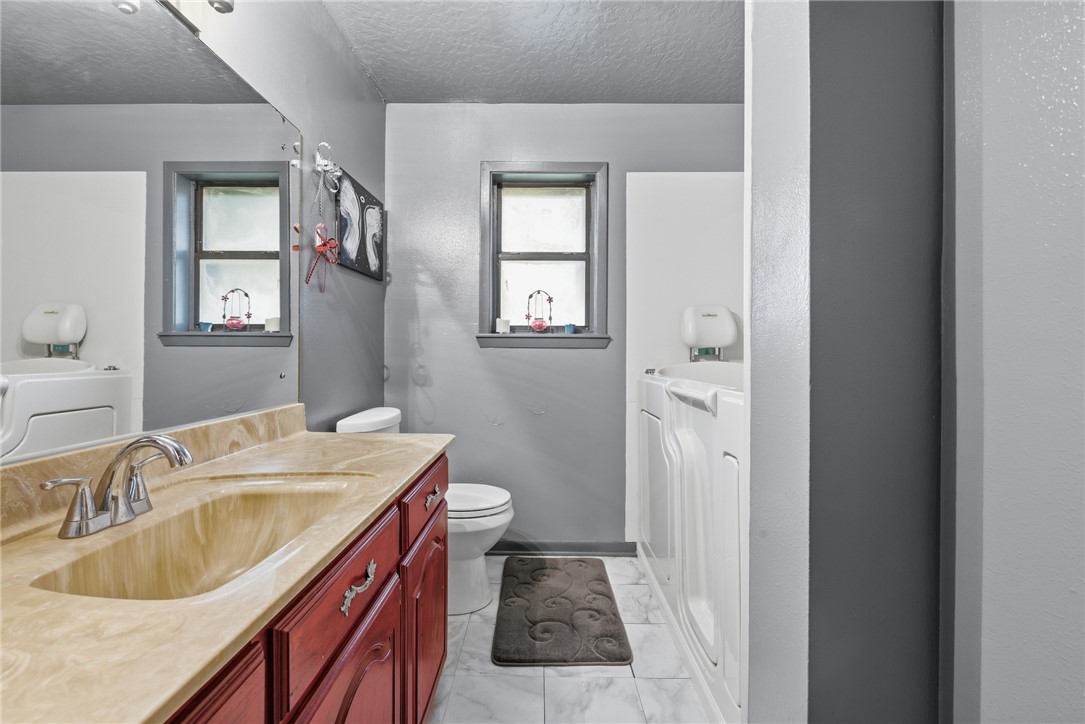 706 Mesquite Street Calvert, TX 77837 - Photo 19 of 23 a bathroom with a granite countertop sink toilet and shower