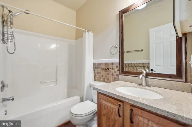 a kitchen with stainless steel appliances granite countertop a refrigerator a sink dishwasher a stove and white cabinets with wooden floor