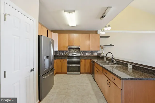 a large kitchen with granite countertop a sink a counter space and cabinets